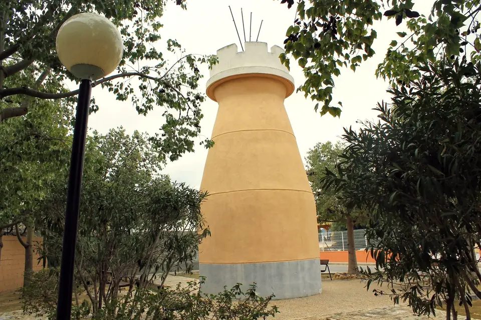 Torreta conocida como El Abuelico entre los árboles de un jardín de Beniel