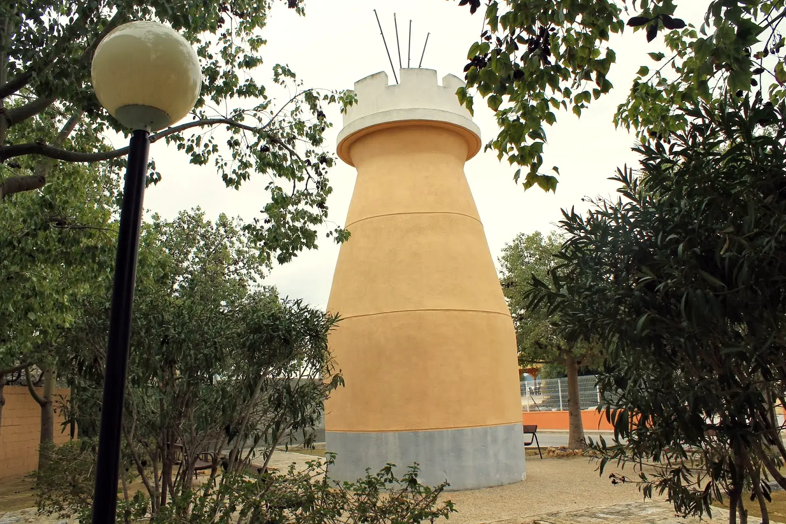 Torreta conocida como El Abuelico entre los árboles de un jardín de Beniel