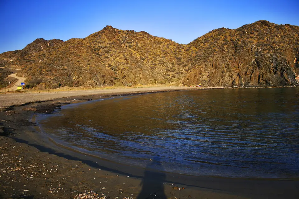 Playa de arena oscura bajo los cerros de Calnegre
